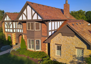 Aerial view of a Tudor-style home featuring exposed timber framing, brick and stone facades, and a complex, multi-gabled roof.