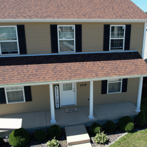 A beige two-story townhouse with a covered entryway and a 